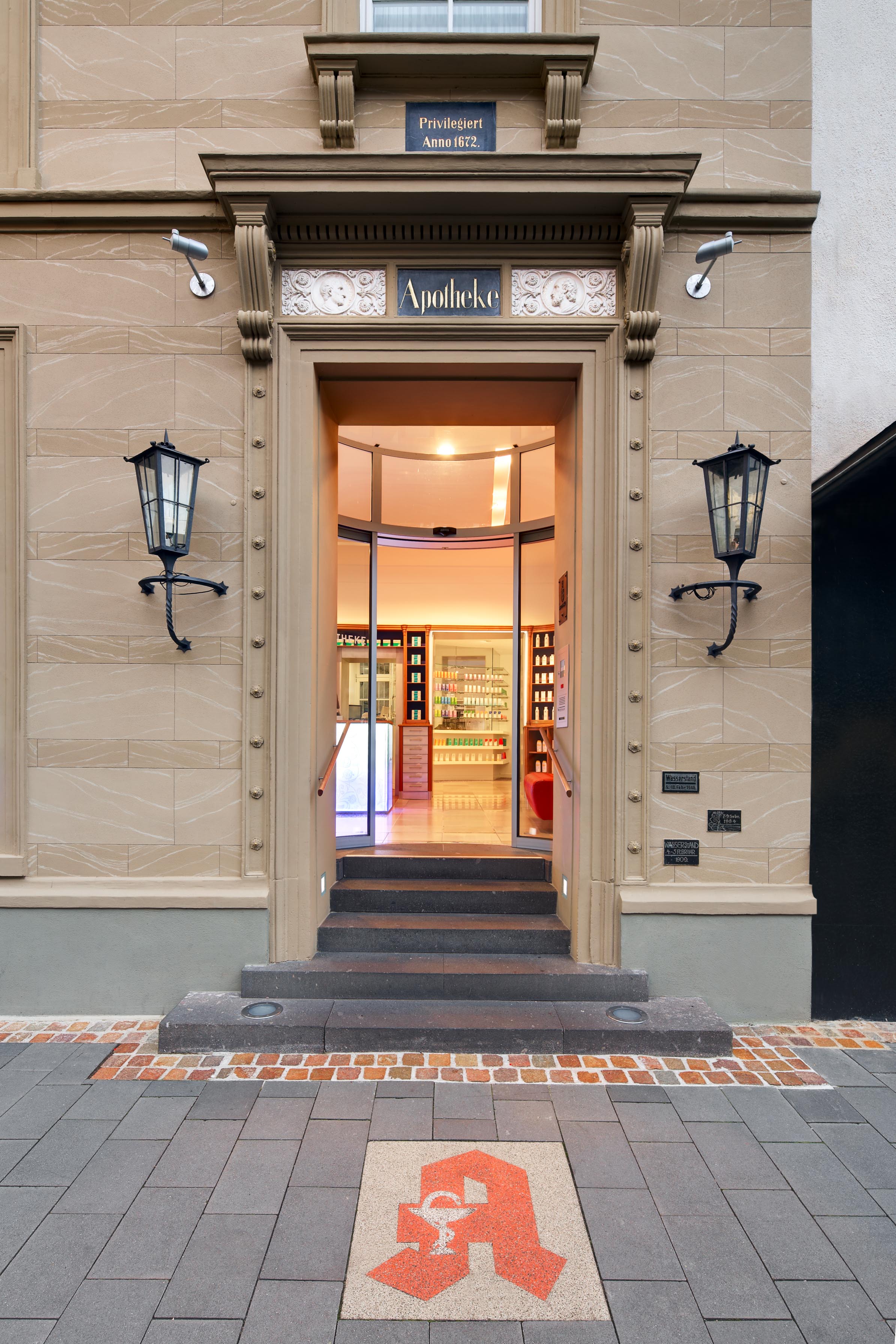 Entrance to Wuth Official Pharmacy with historic flood level markers on the façade