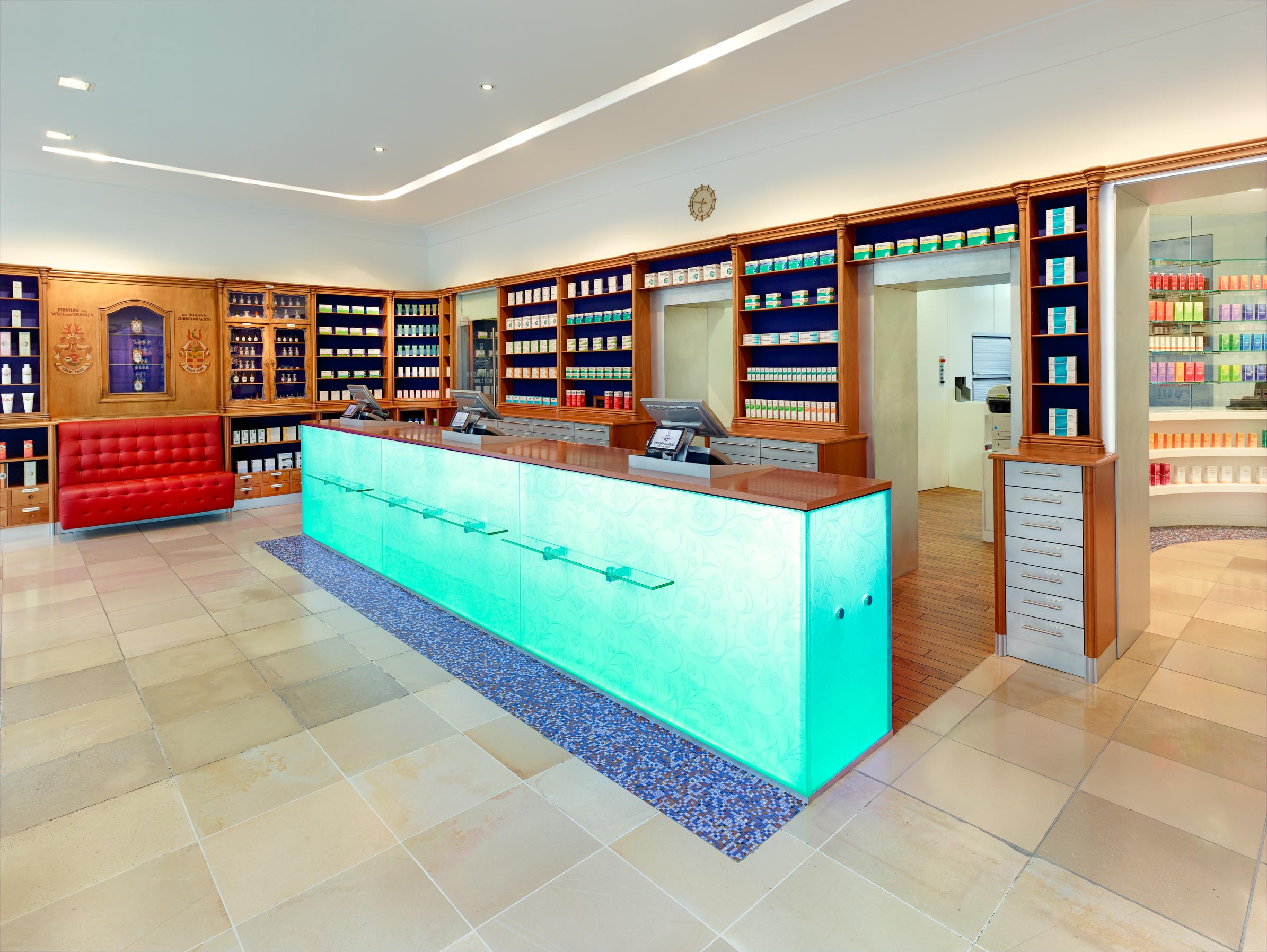 Prescription counter with coloured LED edge lighting in front of the historic medicine display