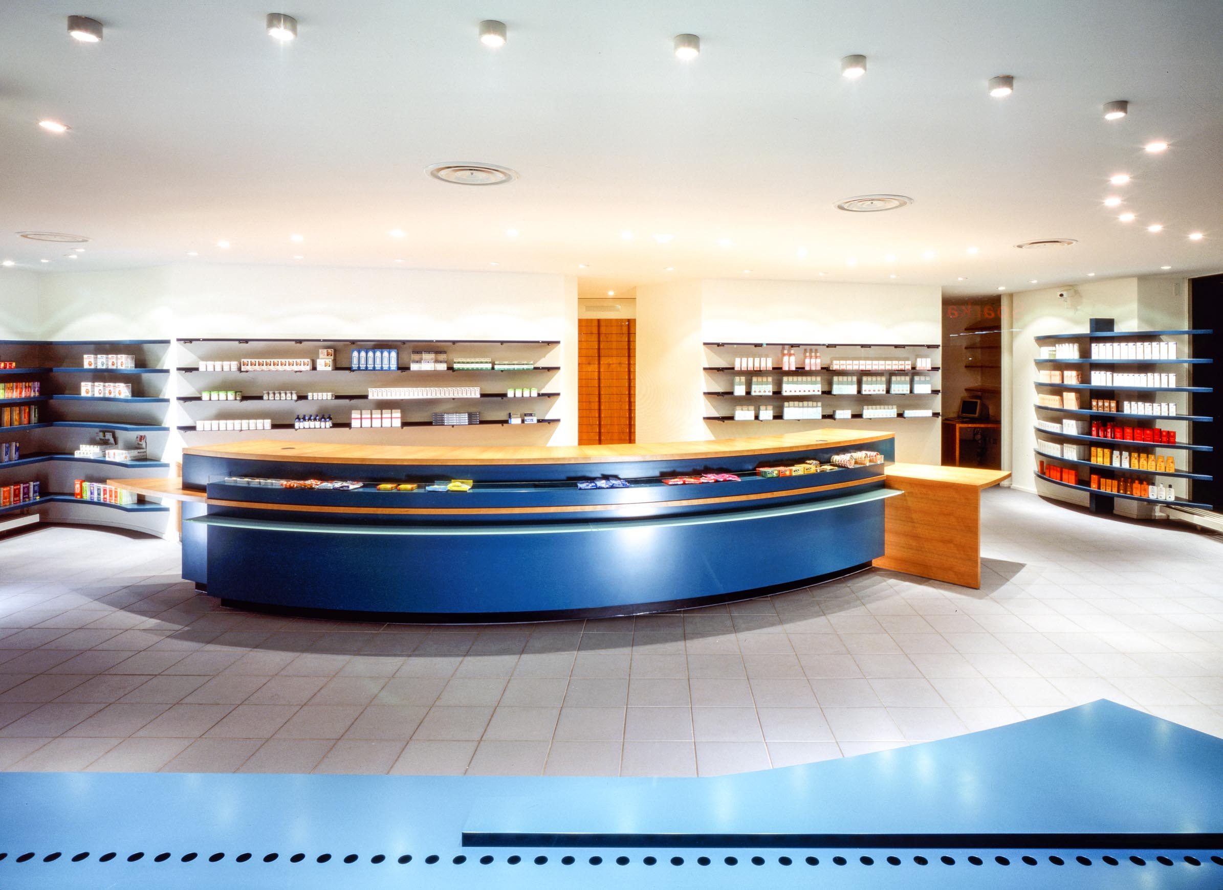 Überblick über die Offizin der Elefanten-Apotheke in Gladbeck mit geschwungenem blauem Handverkaufstisch und umlaufender Sichtwahl