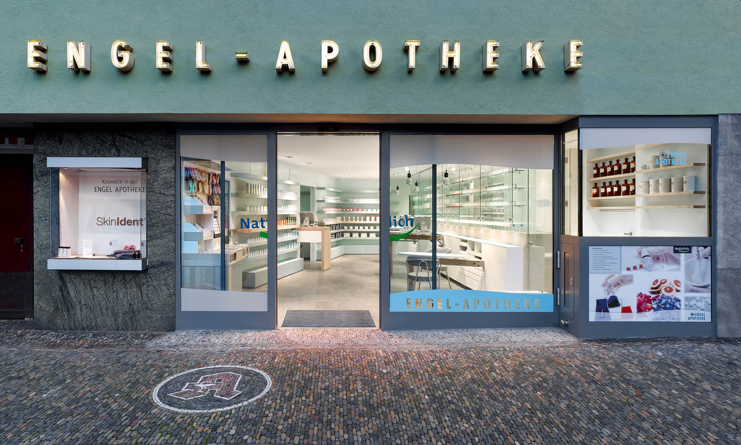 Fassade der Engel-Apotheke in Freiburg mit Blick in die helle Offizin